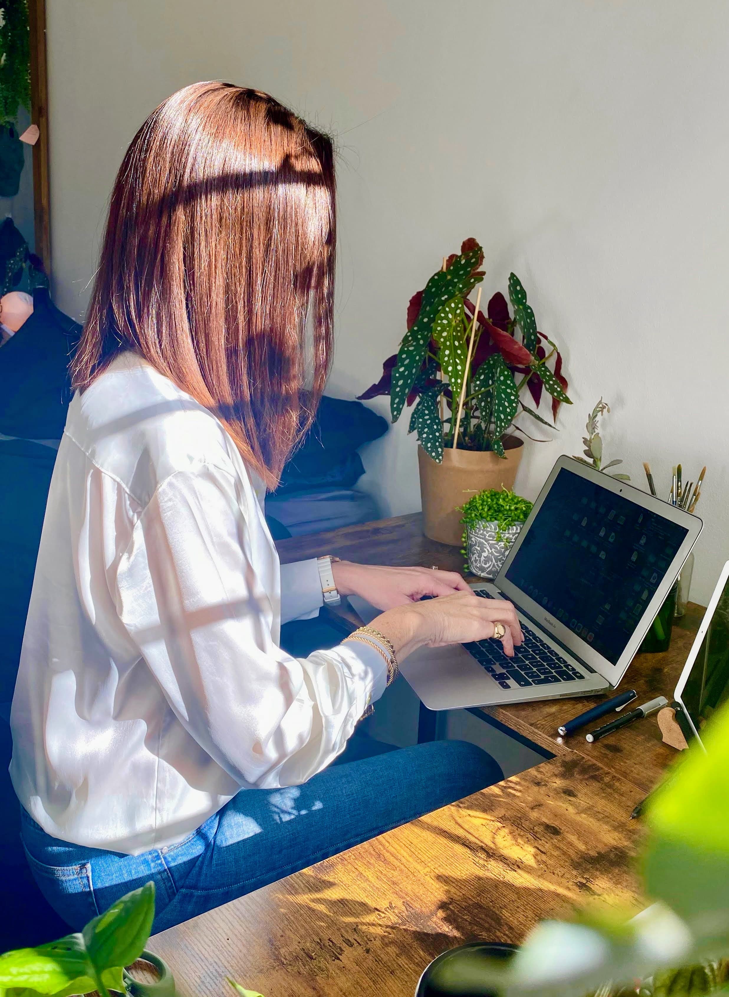 woman sitting at a desk, typing on a laptop